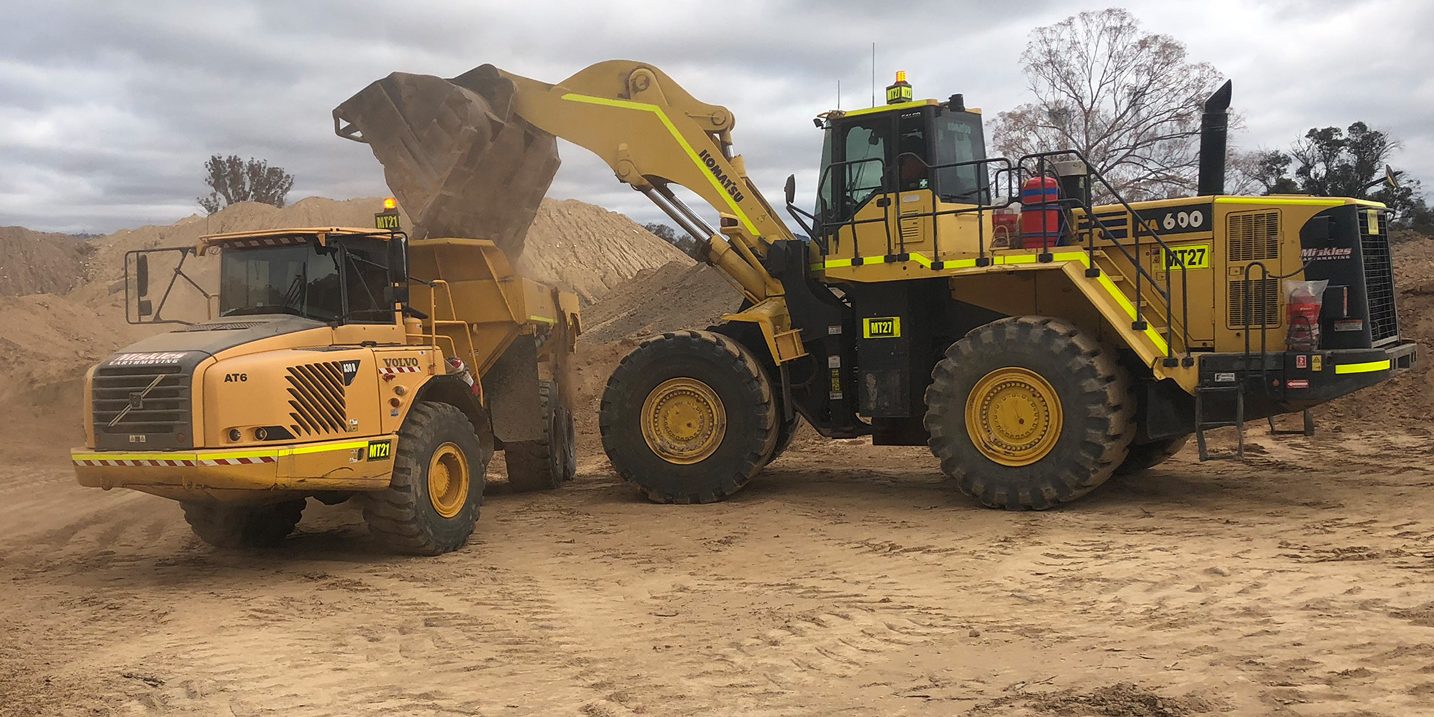 Yellow Komatsu machines excavating dirt